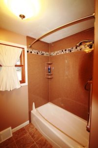 bathroom features a handheld shower in satin nickel, matching grab bar, and small water diverters