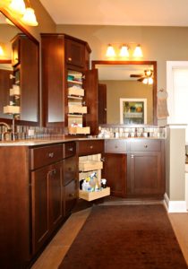 roll-out shelves in corner dark brown vanity cabinet in remodeled bathroom
