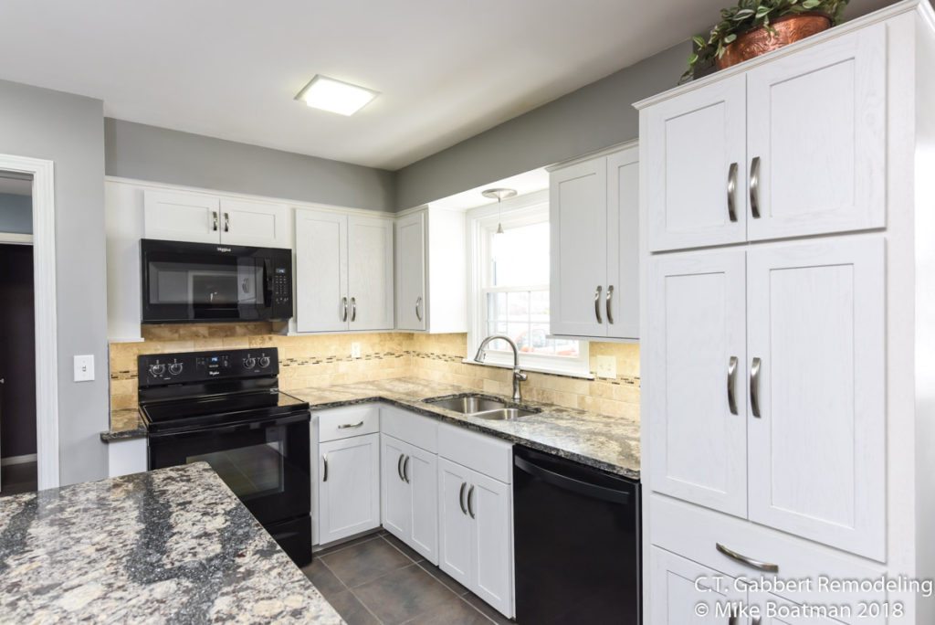 high contrast kitchen with white perimeter cabinets black island and quartz countertops