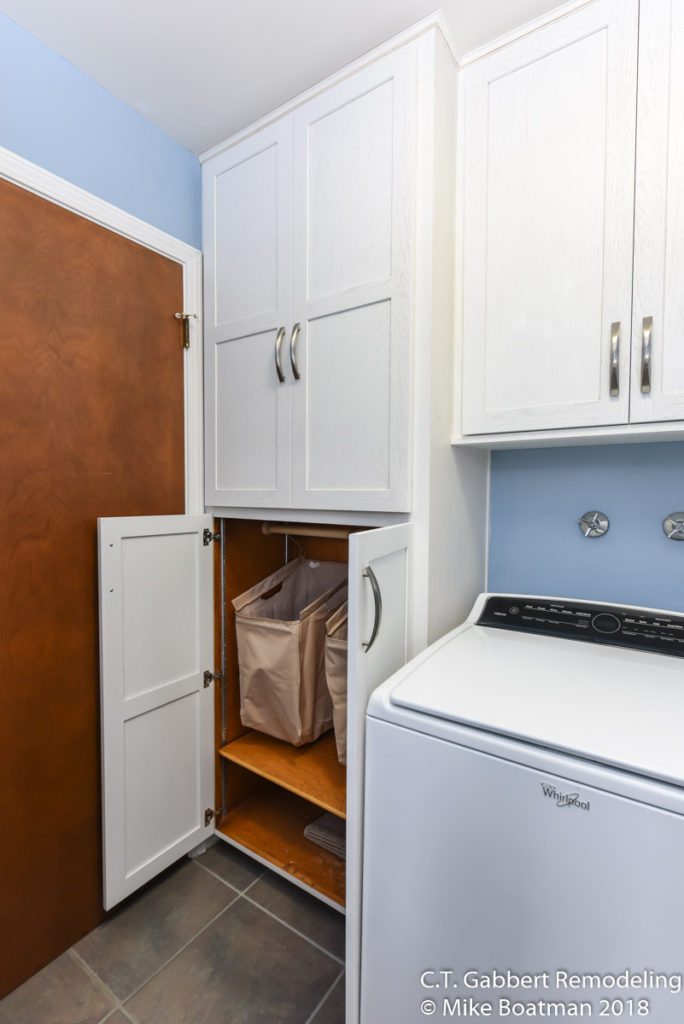 hidden storage in a clean white laundry room