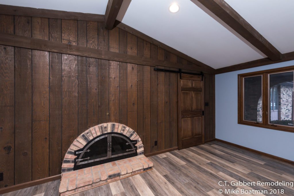 sliding barn door next to wood fireplace in open living room