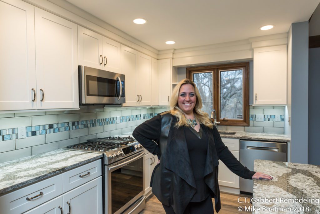 proud homeowner in her newly remodeled white and bright kitchen