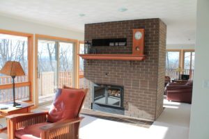 old fireplace in middle of living room with floor to ceiling windows