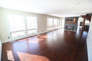 spacious open living room with floor to ceiling windows and wood floors