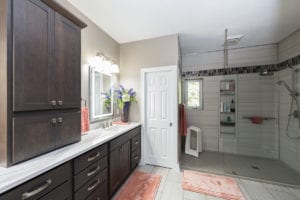 light bright bathroom with brown cabinets pink rugs and walk in shower
