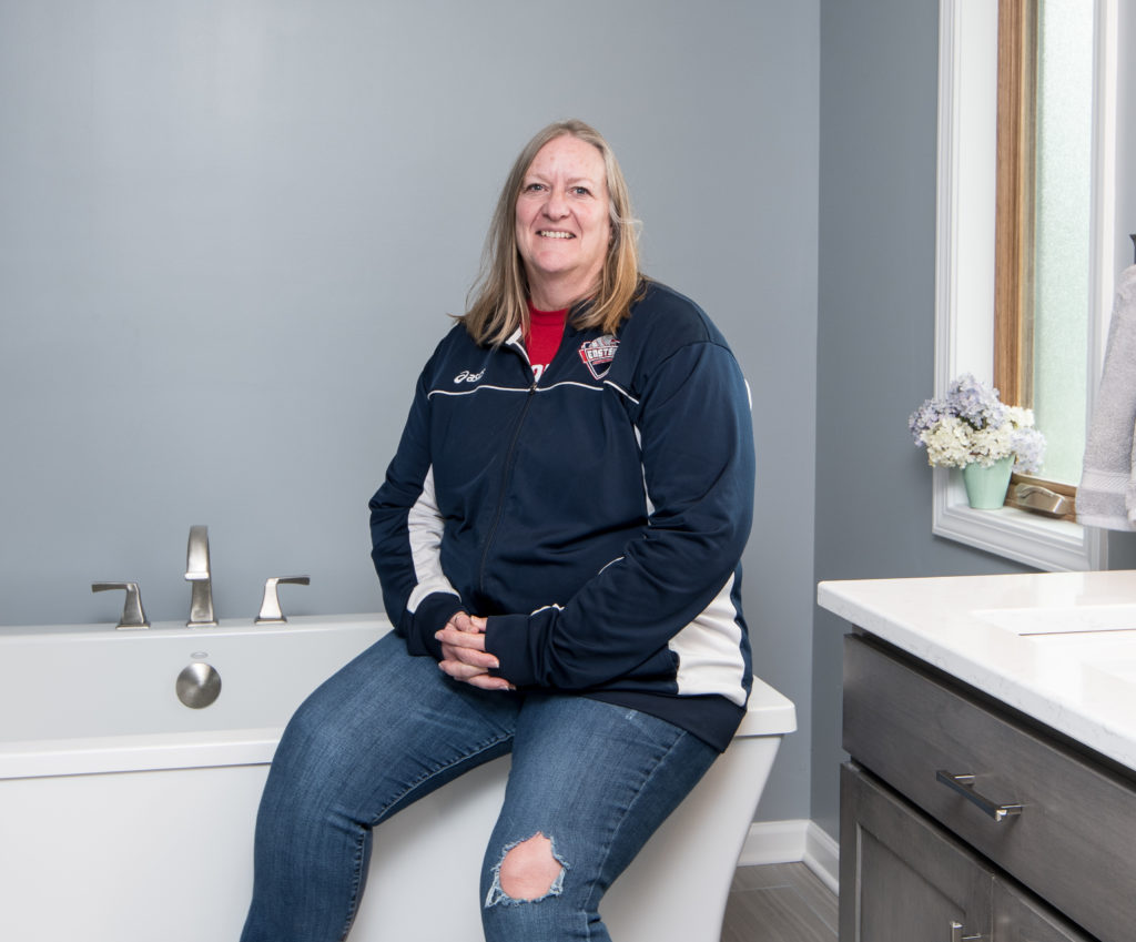 Happy customer sitting on her new tub in her new bathroom
